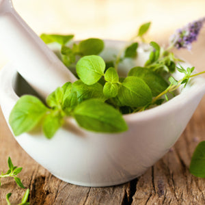 Fresh herbs in a white mortar and pestle